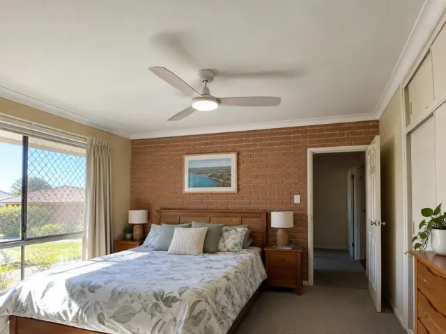 Ceiling fan in a bedroom with brick feature wall and bedside lamps in Marks Point