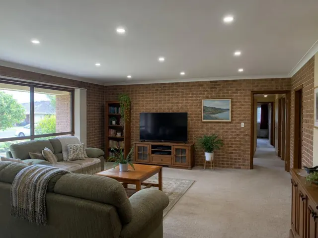 Living room with recessed ceiling downlights, brick walls and carpet in Croudace Bay